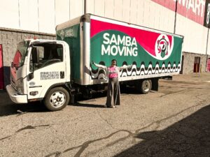 Young female standing in front of branded Samba Moving truck