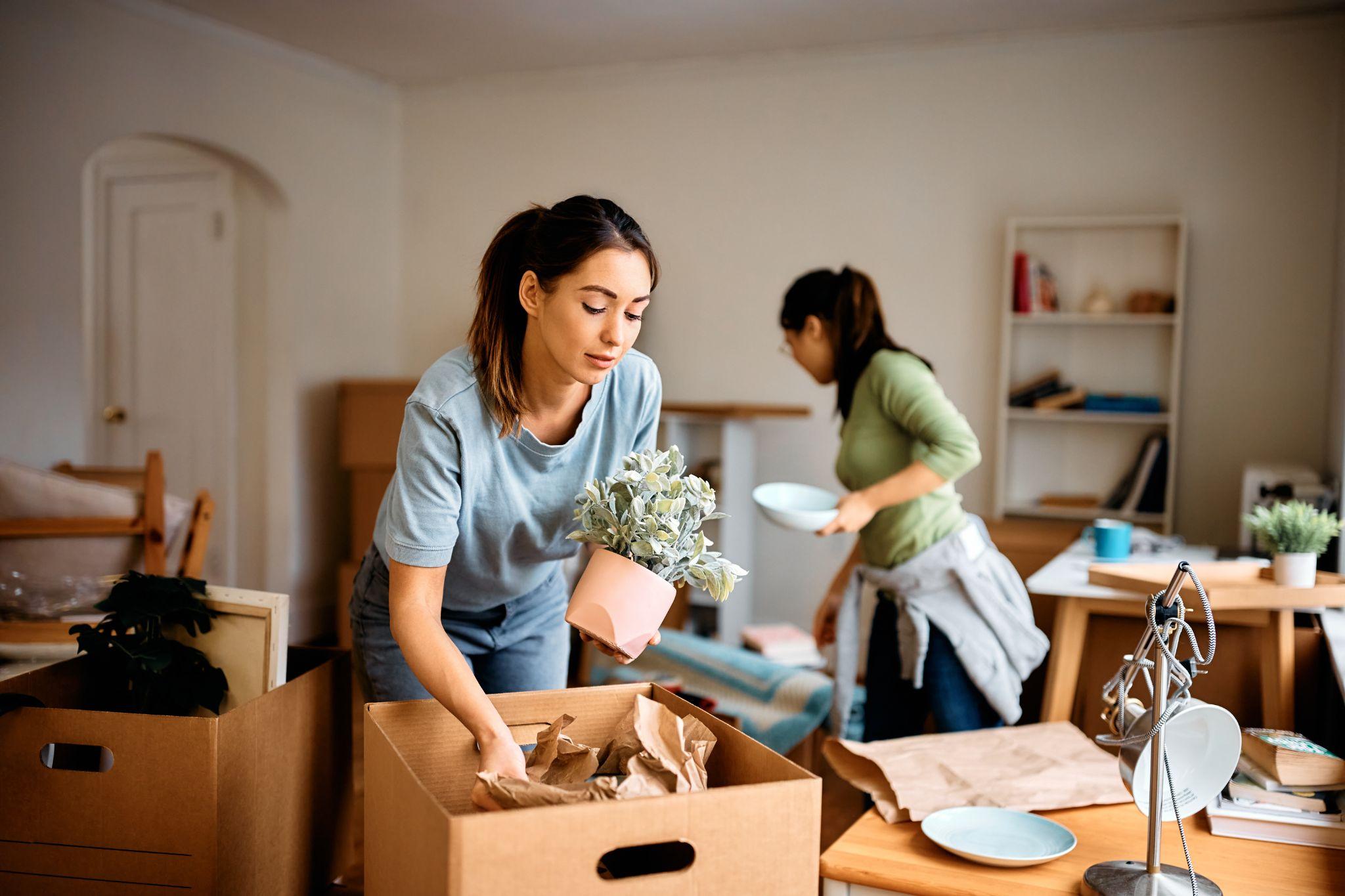 two young women packing boxes in an apartment getting ready to move