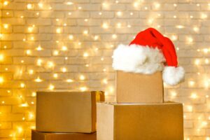 Blank brown freight box with Santa Claus hat on top, brick wall with Christmas lights on background