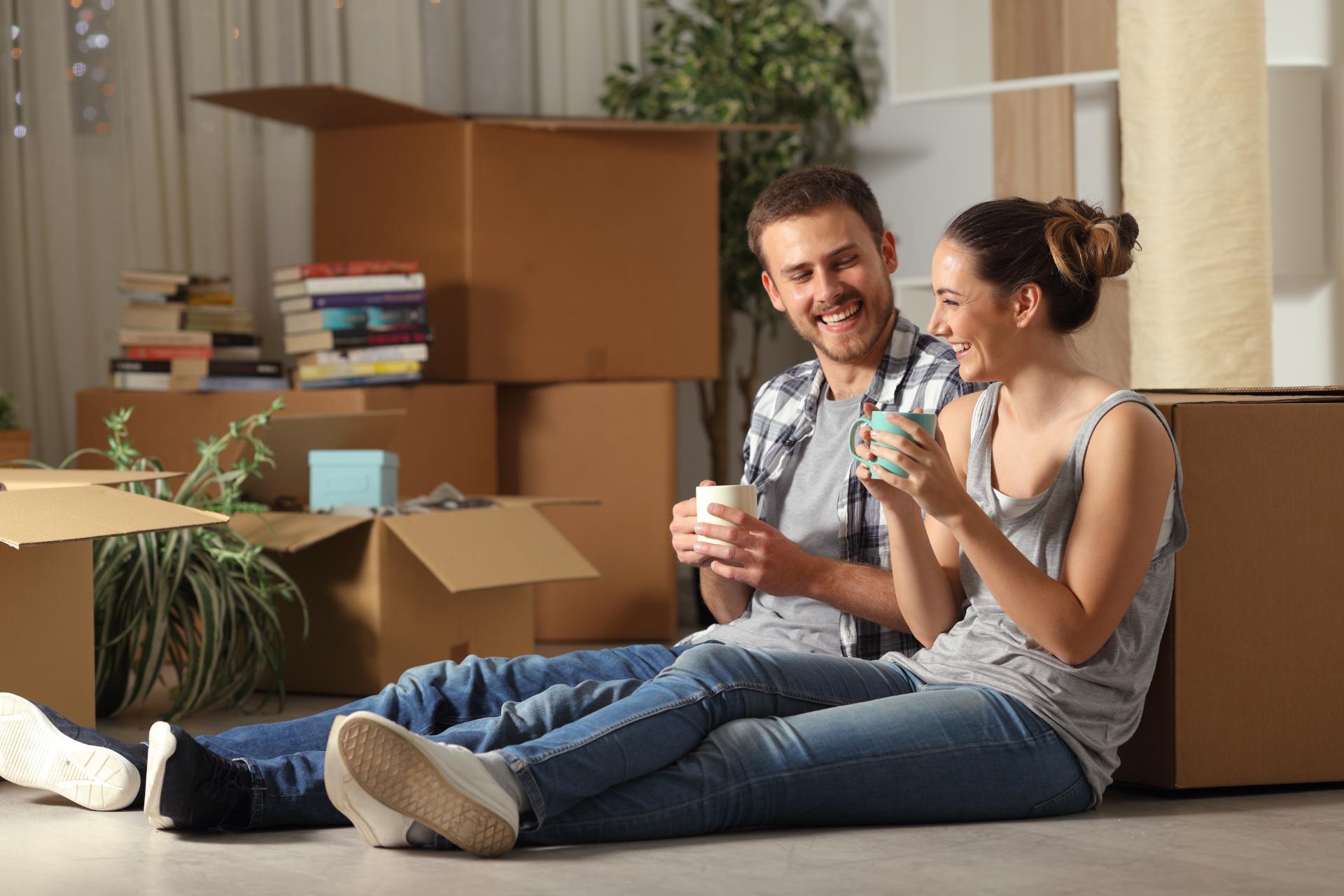 couple sitting next to moving boxes unpacking