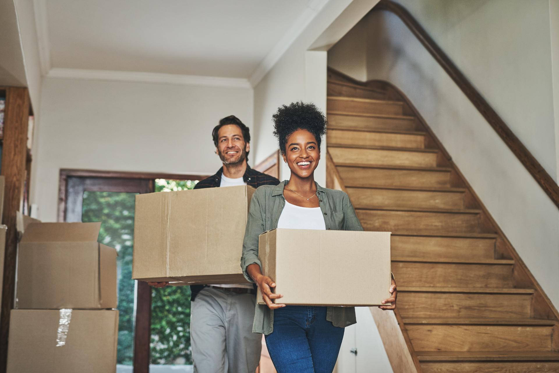 couple carrying moving boxes into new home