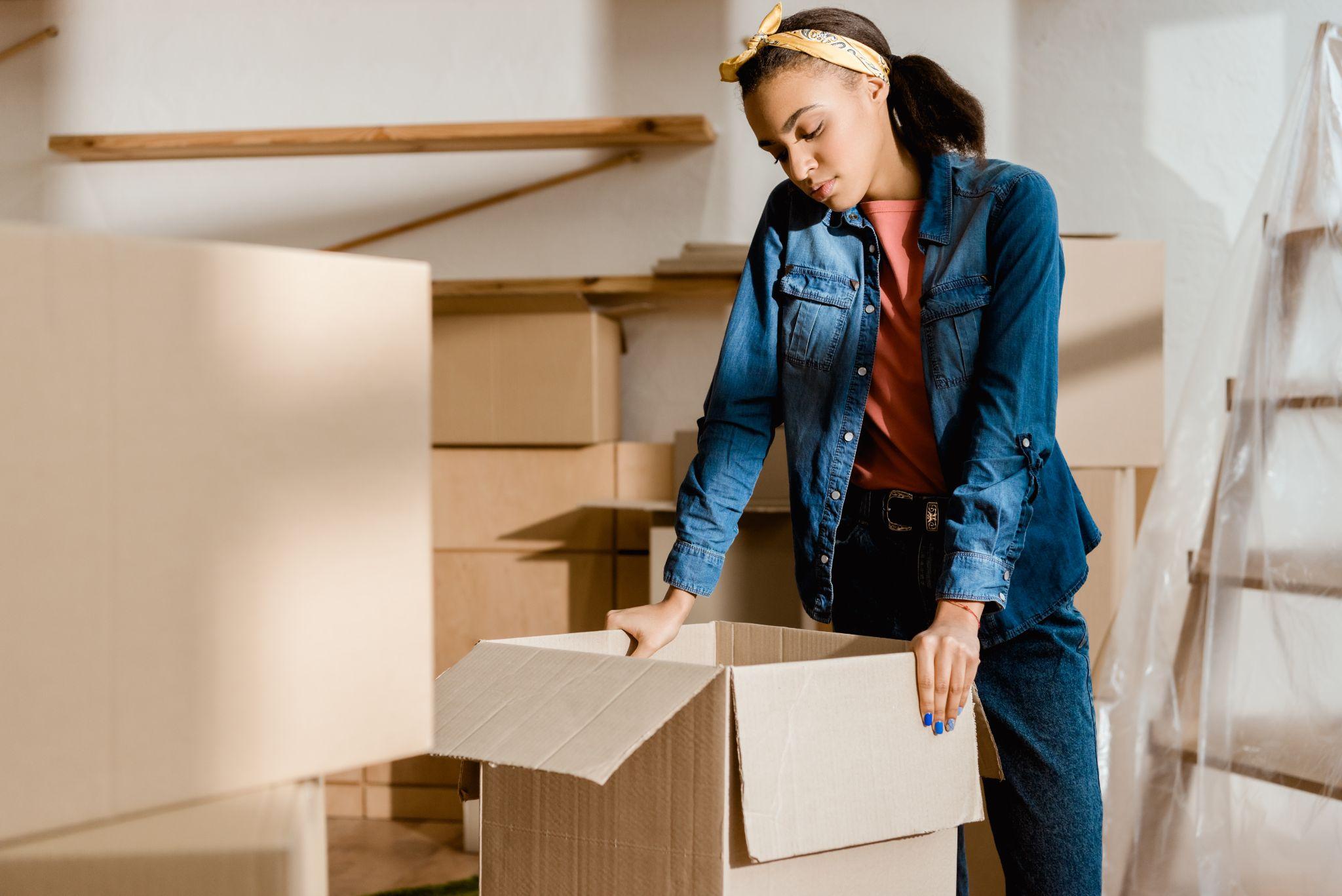 Upset girl unpacking cardboard boxes in new apartment